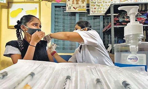 A health worker vaccinates a student against Covid-19 in a school in Bengaluru on Monday. The city saw 1,041 fresh cases | Express
