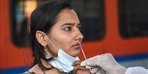A health worker collects a swab sample of a traveler to test for COVID-19. (Photo| PTI)