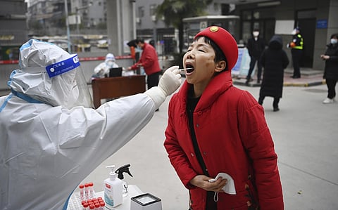 In this photo released by China's Xinhua News Agency, a worker wearing protective gear gives a COVID-19 test to a woman at a testing site in Xi'an in northwestern China's Shaanxi Province. (AP)