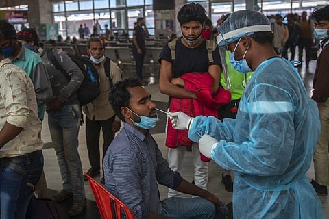 A health worker collects a swab sample from a traveler at a railway station to test for COVID-19, before he is allowed entry into the city, in Mumbai. (Photo | AP)