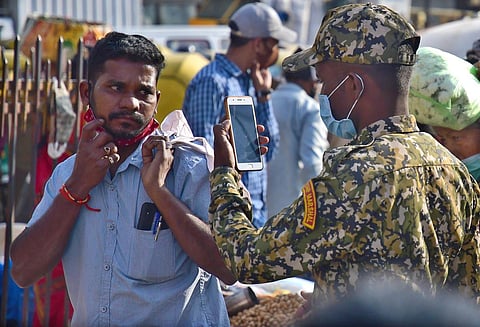 A BBMP marshal takes photos of a man not wearing a mask, to impose a fine, at KR Market in Bengaluru on Tuesday. (Photo | Shriram BN, EPS)