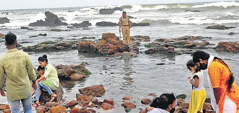 A policewoman stands guard on a rock at RK Beach in Vizag to prevent visitors from entering the sea. (Photo | EPS, G Satyanarayana)