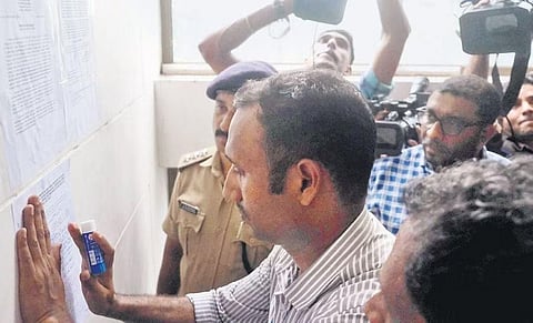 NIA officials sticking  notices at the state committee office of the Popular Front of India at Meenchanda, Kozhikode on Friday | Express