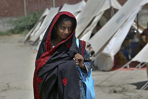 Flood victim Rajul Noor walks towards her tent school at a relief camp, in Dadu, a district of southern Sindh province, Pakistan, Sept. 23, 2022. (Photo | AP)