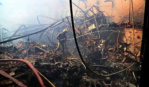 A firefighter tries to douse a fire that broke out at a godown of a film production house, at Tollygunge area in Kolkata (Photo | PTI)