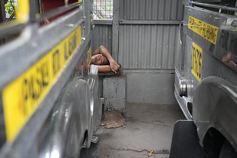 A man sleeps beside jeepneys waiting for passengers at a terminal in Pasay, Philippines. (Photo | AP)