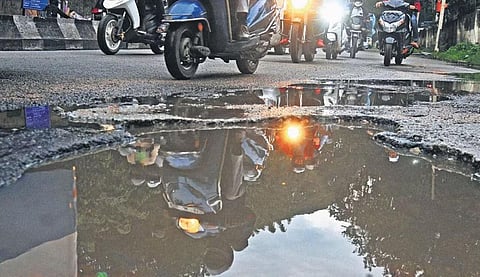 Two-wheelers precariously negotiate a water-filled pothole on Jayamahal Road in Bengaluru on Tuesday | vinod kumar t
