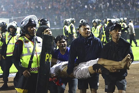 Soccer fans carry an injured man following clashes during a soccer match at Kanjuruhan Stadium in Malang, East Java, Indonesia, Saturday, Oct. 1, 2022. (Photo | AP)