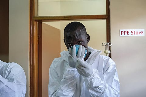 A doctor puts on protective equipment as he prepares to visit a patient in the isolation section of Entebbe Regional Referral Hospital in Entebbe, Uganda, Oct. 20, 2022. (Photo | AP)