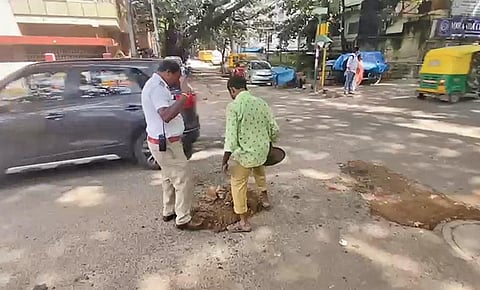 Traffic police personnel get a pothole fixed on Jeevan Bima Nagar Main Road in Bengaluru on Monday | EXPRESS