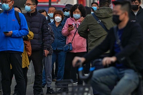 Residents wearing face masks wait in line to get their routine COVID-19 throat swabs tests at a coronavirus testing site in Beijing, Tuesday, Oct. 25, 2022. (Photo | AP)