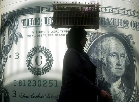 An Egyptian vendor walks past a poster showing a U.S. dollar outside an exchange office in Cairo, Nov. 9, 2016. (File Photo|AP)