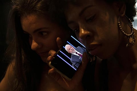 Women listen on a mobile phone to an interview of former president Lula da Silva with Jornal Nacional on TV Globo, outside a bar in Rio de Janeiro, Brazil, Thursday, August 25, 2022. (Photo | AP)