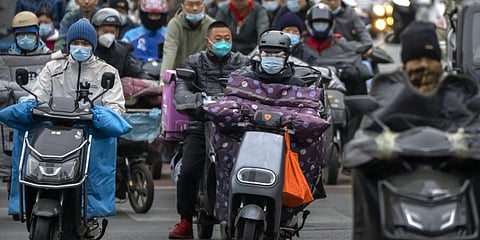 Commuters wearing face masks ride scooters along a street in the central business district in Beijing. (Photo | AP)