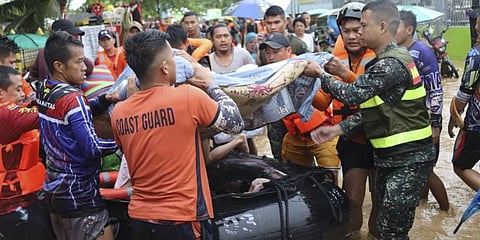 Photo provided by the Philippine Coast Guard, rescuers carry a resident to safer grounds as floods rose due to Tropical Storm Nalgae.(Photo | AP)