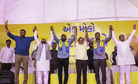 Delhi Chief Minister and Aam Aadmi Party national convenor Arvind Kejriwal raises hands newly-joined party members Rithibhai Malaviya and Alpeshbhai Katharia in Bhavnagar. (Photo | PTI)