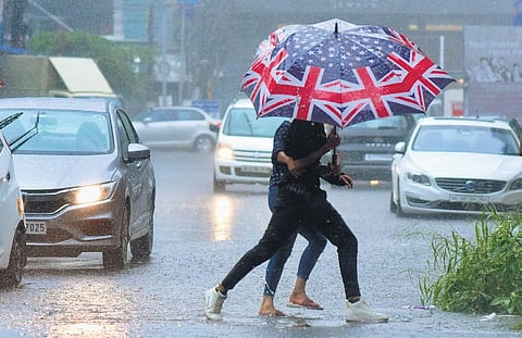 Two youngsters cross a busy road holding an umbrella amid heavy rain in Kochi on Sunday morning. (Photo | A Sanesh)