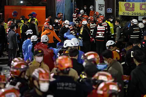Rescue workers try to carry victims near the scene where scores of people died and were injured in Seoul, South Korea, Sunday, Oct. 30, 2022. (Photo | AP)