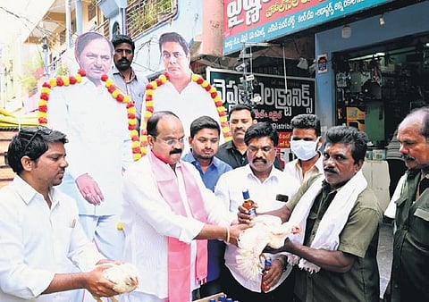 TRS leader Rajanala Srihari hands over a chicken and a 180 ml liquor bottle to a worker in Warangal on Tuesday