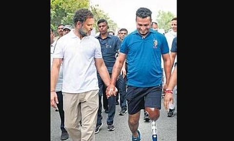 Rahul walks with supporter, a specially-abled person on Friday