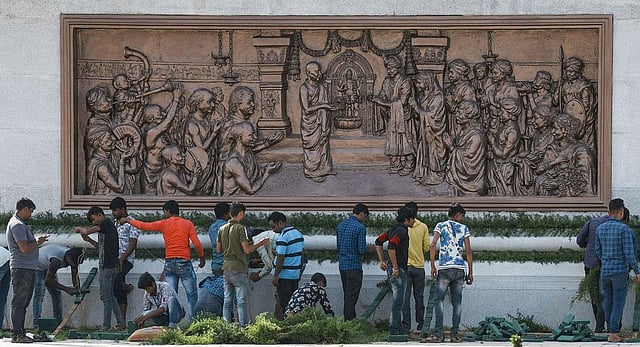 Workers stand at the pedestal of the 108 feet statue of Nadaprabhu Kempegowda at Kempegowda International Airport in Bengaluru. (Photo | PTI)