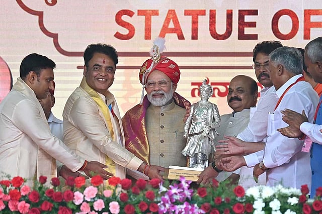 Prime Minister Narendra Modi being presented a memento during a public meeting after the inauguration of Terminal 2 of Kempegowda International Airport and unveiling of 108 feet-tall bronze statue of Nadaprabhau Kempegowda, called 'Statue of Prosperity', in Bengaluru. Karnataka CM Basavaraj Bommai is also seen. (Photo | Shashidhar Byrappa, EPS)