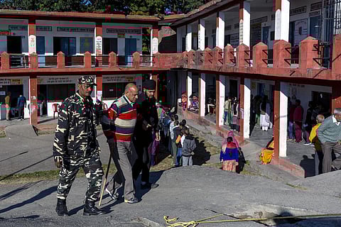 Security personnel assists an elderly voter as he arrives at a polling station to cast his vote for the Himachal Pradesh Assembly elections, near Palampur. (Photo | PTI)