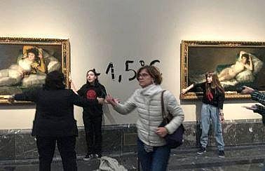 The pic shows two activists glued by a hand to the frames of two paintings by Spanish master Francisco Goya at the Prado museum in Madrid. (Photo | AFP)