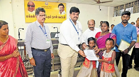 Collector Dr T Prabhushankar handing over the order for a free house patta to Chitra and her two daughters at Karur collectorate on Monday | Express