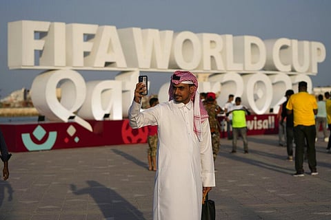 A man takes a selfie with a sign reading in English' Fifa World Cup, Qatar 2022' at the corniche in Doha, Qatar, Friday. (Photo | AP)