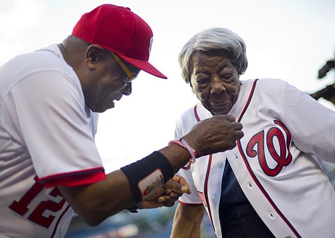 Washington Nationals manager Dusty Baker helps Virginia McLaurin, 107, with her jersey on the field before the Nationals’ baseball game against the St. Louis Cardinals on May 26, 2016. (Photo | AP)
