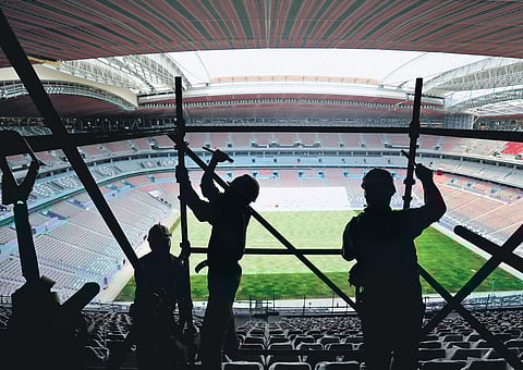 File picture of workers removing scaffolding at the Al Bayt stadium in Al Khor, Qatar. (Photo | AP)