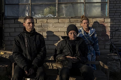 Alesha Babenko, 27, left, Vitaliy Mysharskiy, 14, center, and family member Tanya Babii sit in the yard of the family house in the recently retaken village of Kyselivka, near Kherson (Photo |AP)