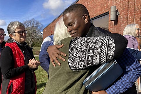 Steven Tendo, center top, hugs Dian Kahn, a member of the Central Vermont Refugee Action Network, outside a federal immigration office, in St. Albans, Vt., Nov. 15, 2022 (Photo | AP)