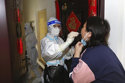 A medical worker takes swab sample from residents during a door-to-door Covid-19 screening in central China's Henan province, Nov. 1, 2022. (Photo | AP)