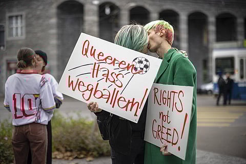 Protestors kiss while holding placards reading 'Shoot out queer hate' and 'Rights not greed' during a rally to raise awareness of the human rights situation of LGBTQ people in Qatar. (File Photo | AP)