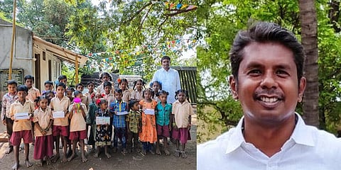 Giridharan with tribal kids in front of the school he helped build  in Maruthavallimedu atop Alleri hills in Vellore. (Photo | Express)