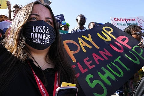 A demonstrator holds a sign that reads 'pay up clean up shut up' during a protest at the COP27 U.N. Climate Summit, Saturday, Nov. 12, 2022, in Sharm el-Sheikh, Egypt. (Photo | AP)