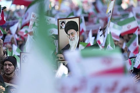 A man holds up a poster of Iranian Supreme Leader Ayatollah Ali Khamenei as the others wave the country's flags during a demonstration in front of the former U.S. Embassy in Tehran, Nov. 4, 2022. (Fil