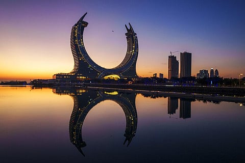 A plane flies over the Crescent Tower Lusail during sunrise in Lusail, Qatar, Nov. 24, 2022. (Photo | AP )