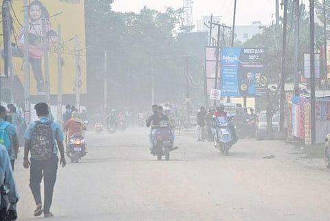 Commuters passing through a road filled with dust; layers of silt accumulated on a road in Cuttack | Express