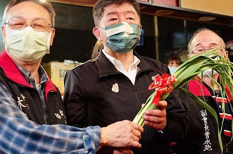 Taipei mayoral candidate Chen Shih-chung (centre) holding scallions while campaigning in Taipei on Nov 8, 2022. (Photo | AFP)