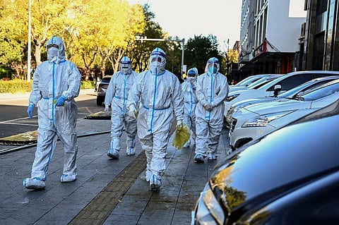 Health workers walk near a residential area placed under lockdown to contain the coronavirus spread in Beijing on Nov. 13, 2022. (Photo | AFP)