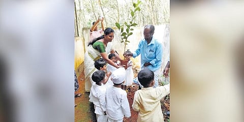 Kannan helps children plant saplings. (Photo |EPS)