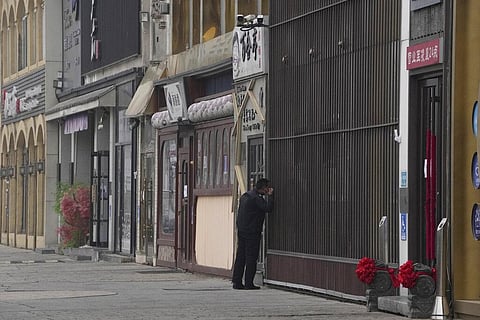 A security guard peers into a store along a stretch of shuttered restaurants in Beijing. (Photo | AP)