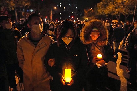 Protesters hold candles as they march in Beijing, Nov. 27, 2022. (Photo | AP)