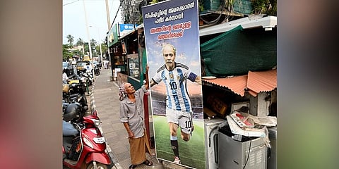 Hameed Karsayi, a cook at a restaurant in Kozhikode, looks at a huge hoarding with his picture in Lionel Messi’s jersey at Vellayil in the district. | E Gokul