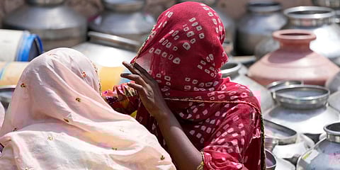 Where're the women to  represent them? Women from a slum wait to collect drinking water from a borewell of a temple complex in Ahmedabad. (File Photo | AP)