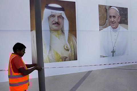 A worker hangs a bar in front of portraits that show Pope Francis, (R), and Bahrain's King Hamad bin Isa Al Khalifa, outside the Cathedral of Our Lady of Arabia in Manama, Nov. 2, 2022. (Photo | AP)