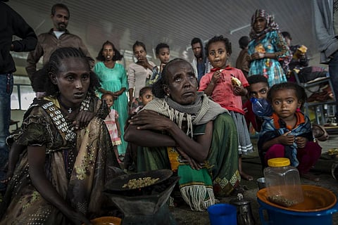Tigrayan women Tarik, 60, center, and Meresaeta, left, who fled from the town of Samre, roast coffee beans over a wood stove in a classroom of a school where they now live.(File Photo | AP)